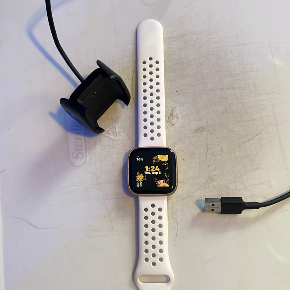 Fitbit Versa 2 with charging cord.